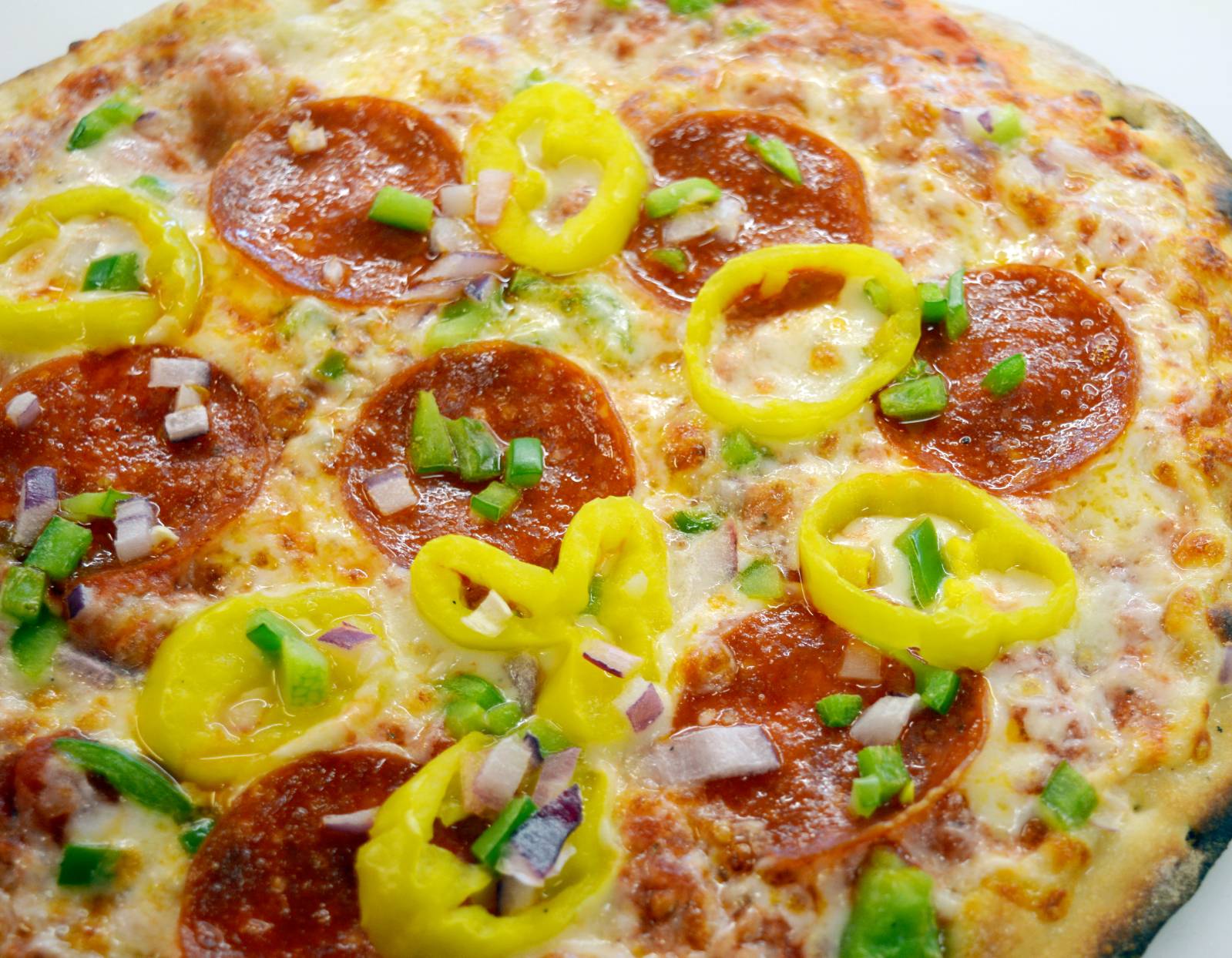 Close-up photograph of a pizza with pepperoni and peppers.