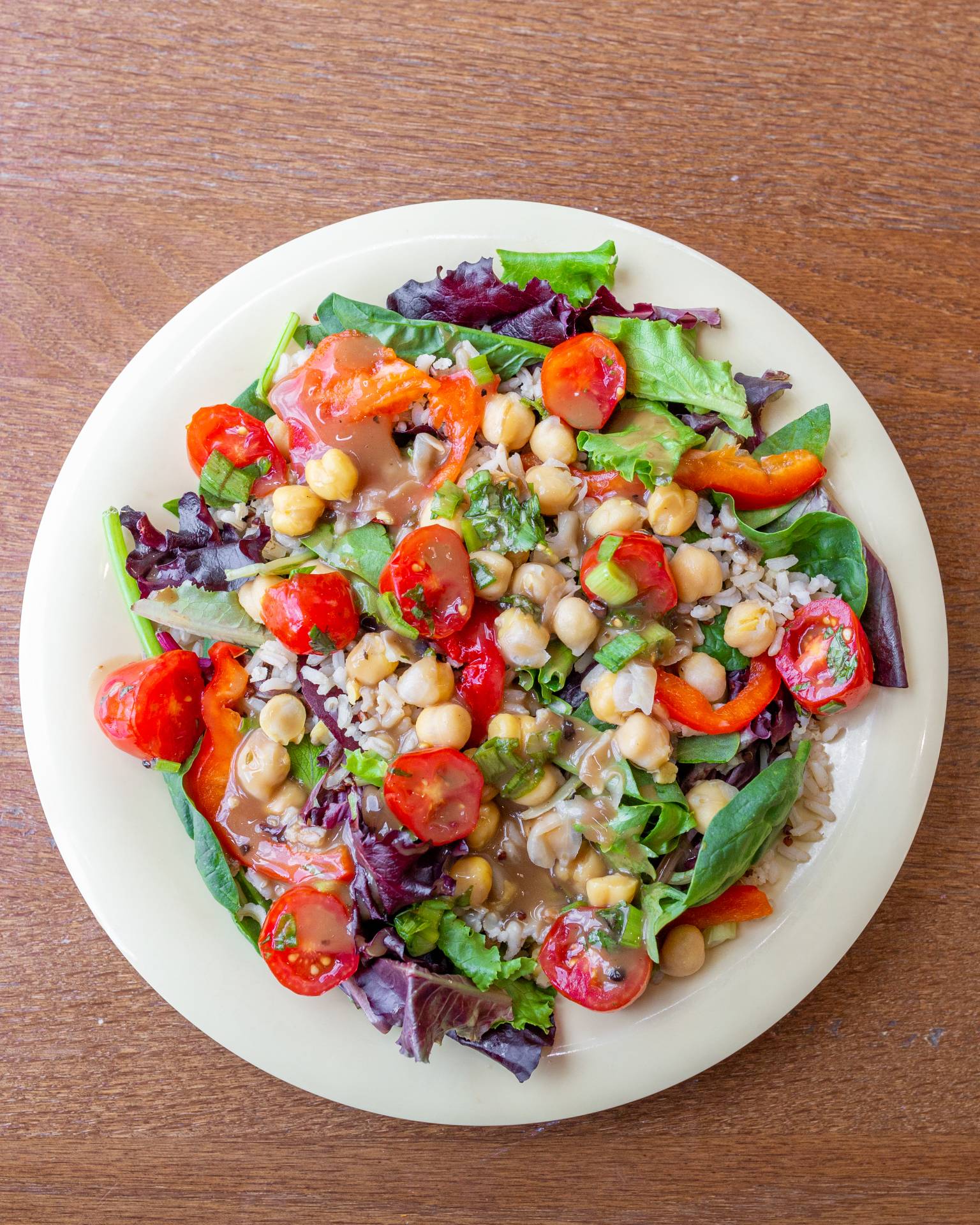 A photograph of a plate with rice, chickpeas, leafy greens, and cherry tomatoes.