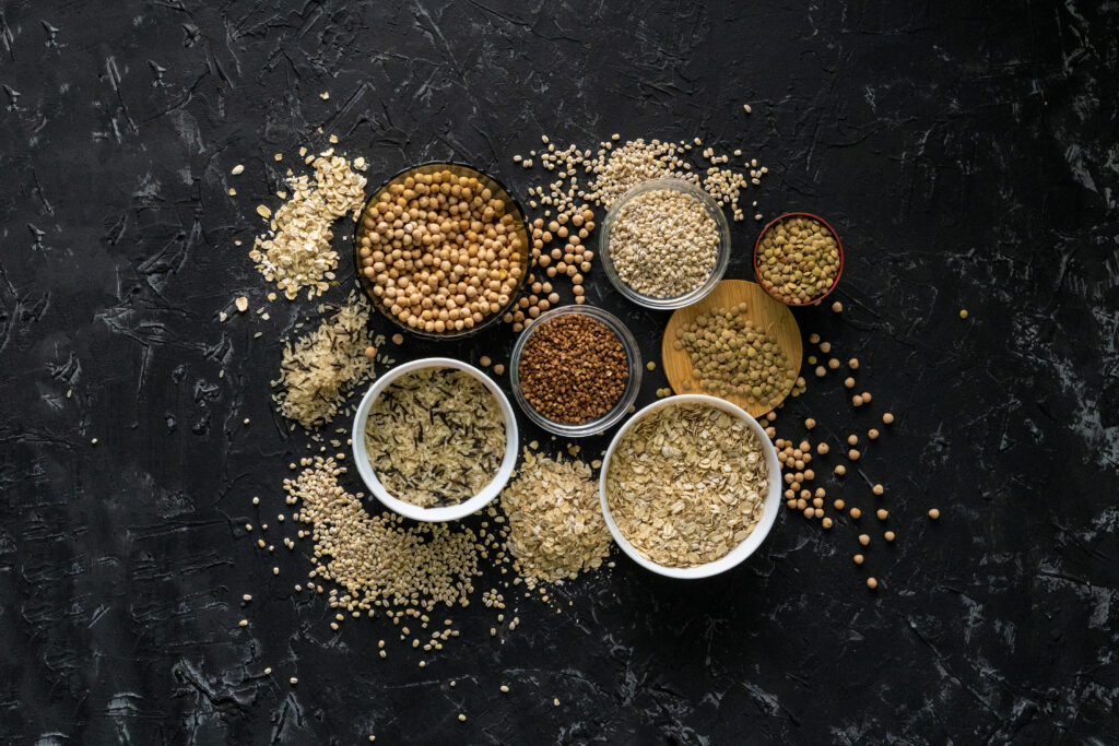 selection of raw uncooked cereals grains in bowls with chickpeas oat lentil rice buckwheat