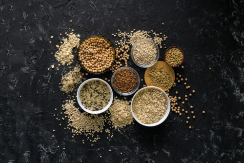 selection of raw uncooked cereals grains in bowls with chickpeas oat lentil rice buckwheat