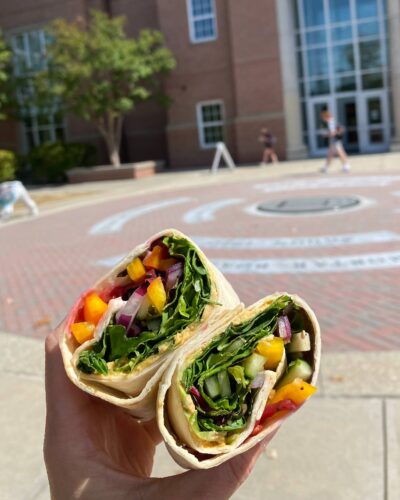 A photograph of a wrap cut in half and held up outside of Tate Student Center.